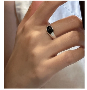 Detail of vintage silver ring with oval black onyx gemstone on person's finger