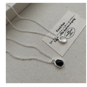 Detail of minimalist S925 sterling silver necklaces with black and white agate pendants