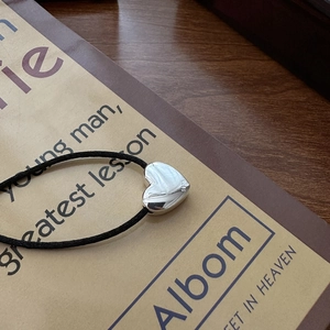S925 sterling silver heart necklace with black cord on book background