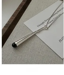Détail macro de la chaîne box en argent S925 et du pendentif en émail noir