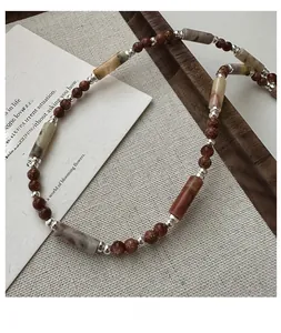 Macro shot of S925 silver necklace with brown stone beads and marble cylinders