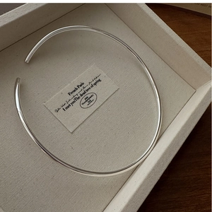 Close-up of a minimalist S925 sterling silver open choker collar necklace on a display tray