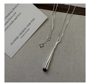 Détail du collier en argent S925 avec pendentif en émail noir sur fond de lin gris chiné