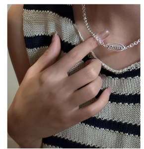 Detailed view of silver S925 loveme letter pendant necklace worn on striped knitwear