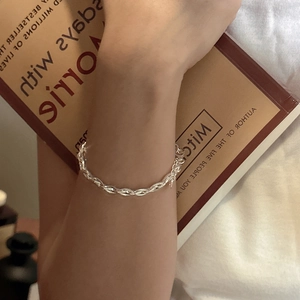Elegant S925 sterling silver braided rope bracelet on a wrist over a book