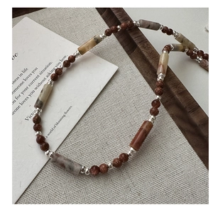 Detail of S925 silver beaded necklace with brown goldstone and textured stone beads