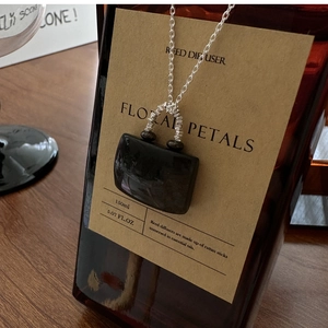 Detailed close-up of a S925 silver necklace with black gemstone pendant on a vintage bottle