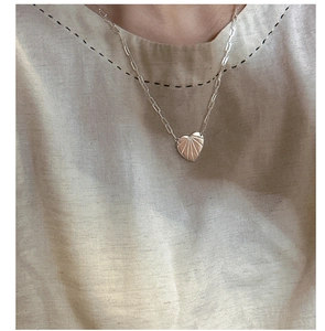 Gros plan d'un pendentif cœur avec texture rayonnante sur une chaîne à trombones