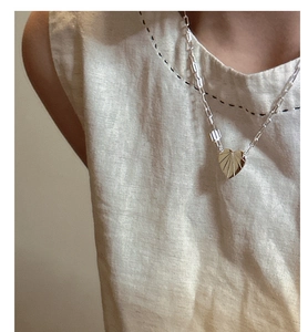 Détail du pendentif cœur doré à texture radiale sur une chaîne style trombone chic