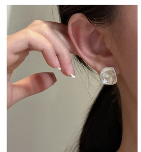 Close-up of a s925 silver irregular square wrinkled earring worn on model ear