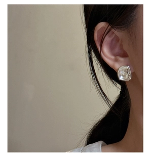 Macro detail of silver square stud earrings with liquid metal rippled texture finish