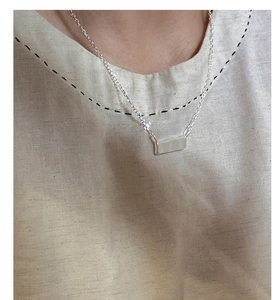 Dettaglio ravvicinato di una collana a barra in argento sterling S925 indossata da modella