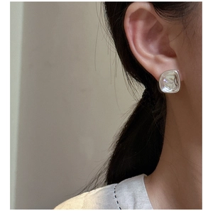 Macro detail of silver geometric square stud earring with hammered metal texture effect