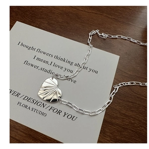 Détail macro d'un pendentif cœur en argent S925 sur une chaîne trombone moderne et chic