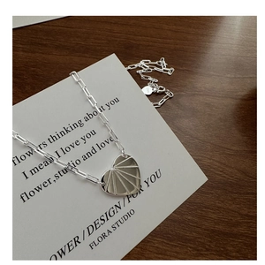 Détail du pendentif cœur en argent S925 avec texture soleil sur une chaîne à maillons carrés