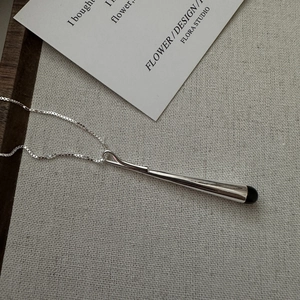 Collier minimaliste en argent S925 avec pendentif linéaire noir sur tissu texturé gris