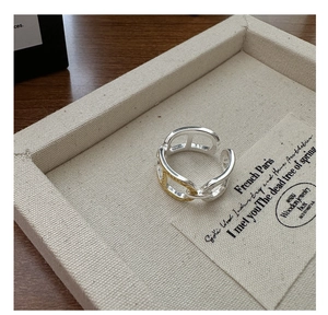 Detailed view of two-tone silver and gold chain link ring on beige fabric display box