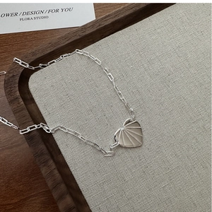 Vue détaillée du collier coeur argenté avec texture soleil et chaîne trombone moderne