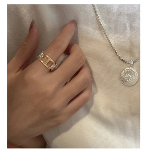 Close-up of golden chain ring and silver sunburst pendant necklace on a model