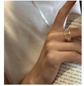 Detail view of a gold-toned pig nose chain ring worn on a finger with lifestyle backdrop