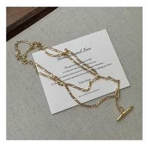 Detailed view of the gold-plated toggle clasp and industrial chain links on a gray fabric