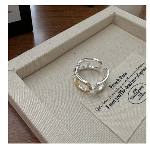 Detail of a two-tone chain link open ring on a textured linen jewelry display tray