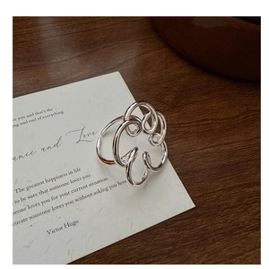 Dettaglio dell'anello floreale astratto in argento S925 con fascia aperta su carta