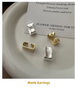 Detail of matte gold and silver ear cuffs with irregular texture on ceramic tray