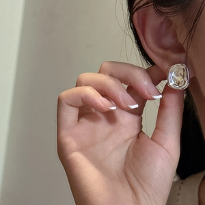 Minimalist s925 sterling silver geometric fold earrings worn on earlobe for display