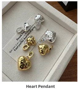 Dettaglio di pendenti a cuore in oro e argento con trame martellate lavorate a mano