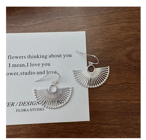 Macro shot of S925 sterling silver fan-shaped earrings on an aesthetic literary card