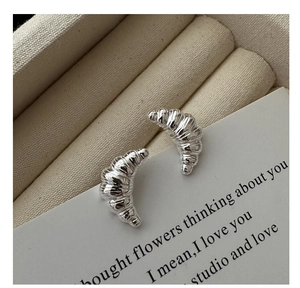 Macro shot of silver croissant earrings with detailed spiral texture on jewelry box