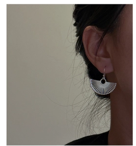 Macro detail of S925 sterling silver fan-shaped earrings worn by a model in profile