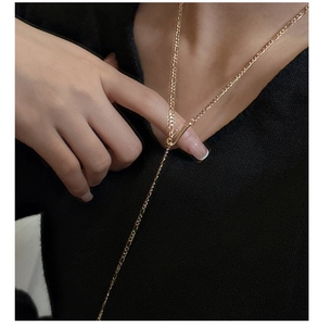 Detail of a gold Figaro Y-lariat necklace worn over a black V-neck top for women