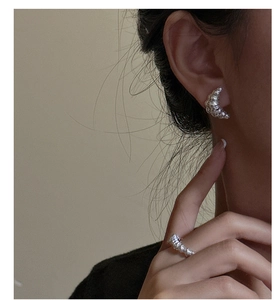 Detailed close-up showing the croissant texture of silver earrings on a model