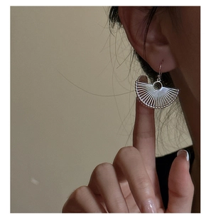 Detail of silver fan-shaped drop earrings featuring radial texture and tiny bead trim