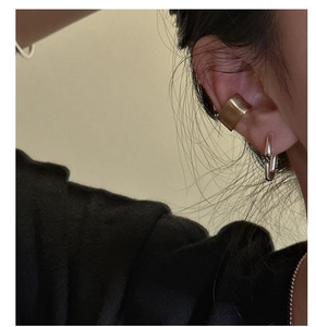 Detail of matte gold cuff and silver ring earring worn on a model's ear