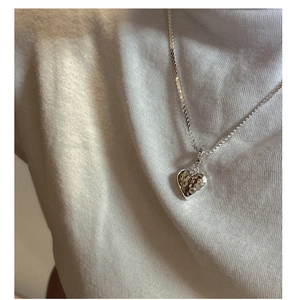 Dettaglio della collana a cuore in argento S925 con texture martellata su modella