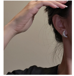 Close-up of S925 sterling silver croissant hoop earring with ribbed texture on model ear