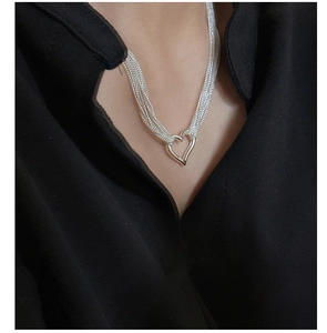Macro detail of layered silver heart necklace on neck showing modern minimalist style