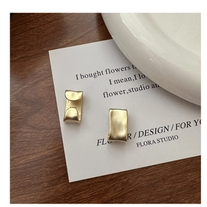 Close-up of matte gold 925 sterling silver square ear cuffs with textured fold design