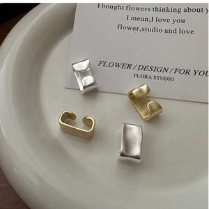 Detailed view of matte gold and silver textured non-piercing ear cuffs on ceramic tray