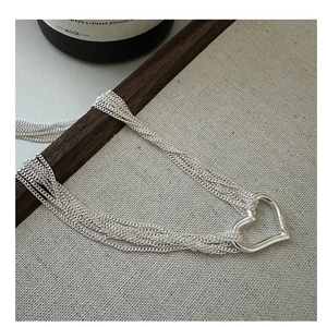 Macro detail of S925 sterling silver multi-strand necklace with open heart pendant