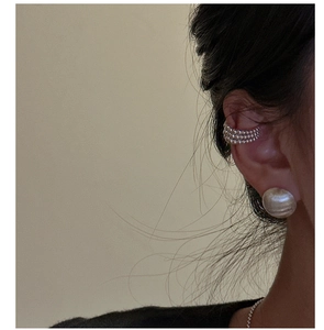 Détail d'une manchette d'oreille à perles argentées et d'un clou en métal brossé