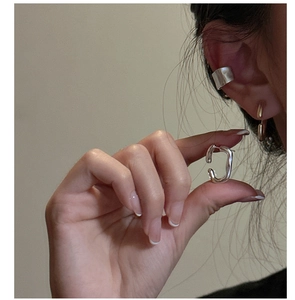 Detail view of S925 sterling silver textured hoop earrings and ear cuffs on a model