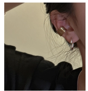 Detail of model wearing a matte gold ear cuff and silver oval stud earring
