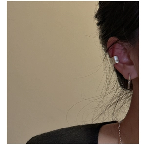 Detail of silver ear cuff with pleated texture and polished finish on female model