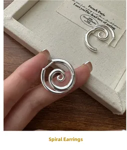 Macro detail of S925 sterling silver spiral earrings with a polished minimalist finish