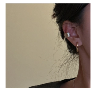 Macro shot of S925 silver textured ear cuff and gold hoop earring worn on ear