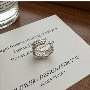 Gros plan de la texture de la bague en perles d'argent multicouches sur carte blanche